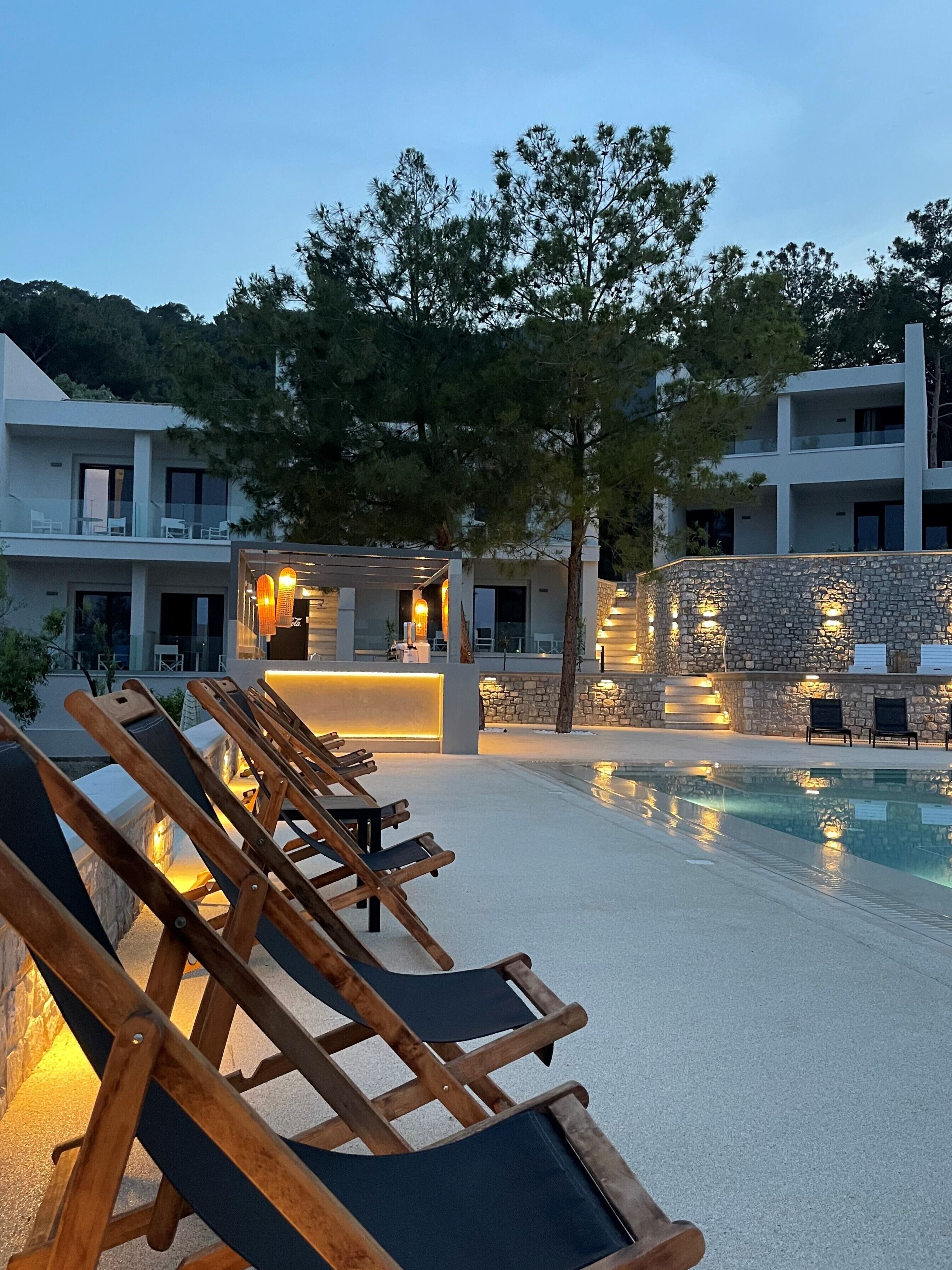 Un resort con piscina, sillas de descanso y un muro de piedra.