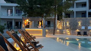 Un resort con piscina, sillas de descanso y un muro de piedra.