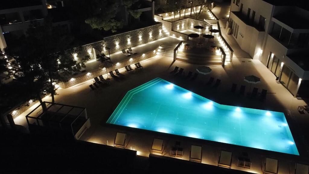 Una piscina al aire libre con sillones de descanso y una terraza solárium.