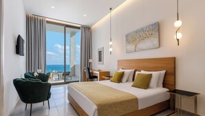 A modern hotel room with a large bed, a desk, and a view of the ocean. - Mythical Coast Wellness Retreat (Lesvos)