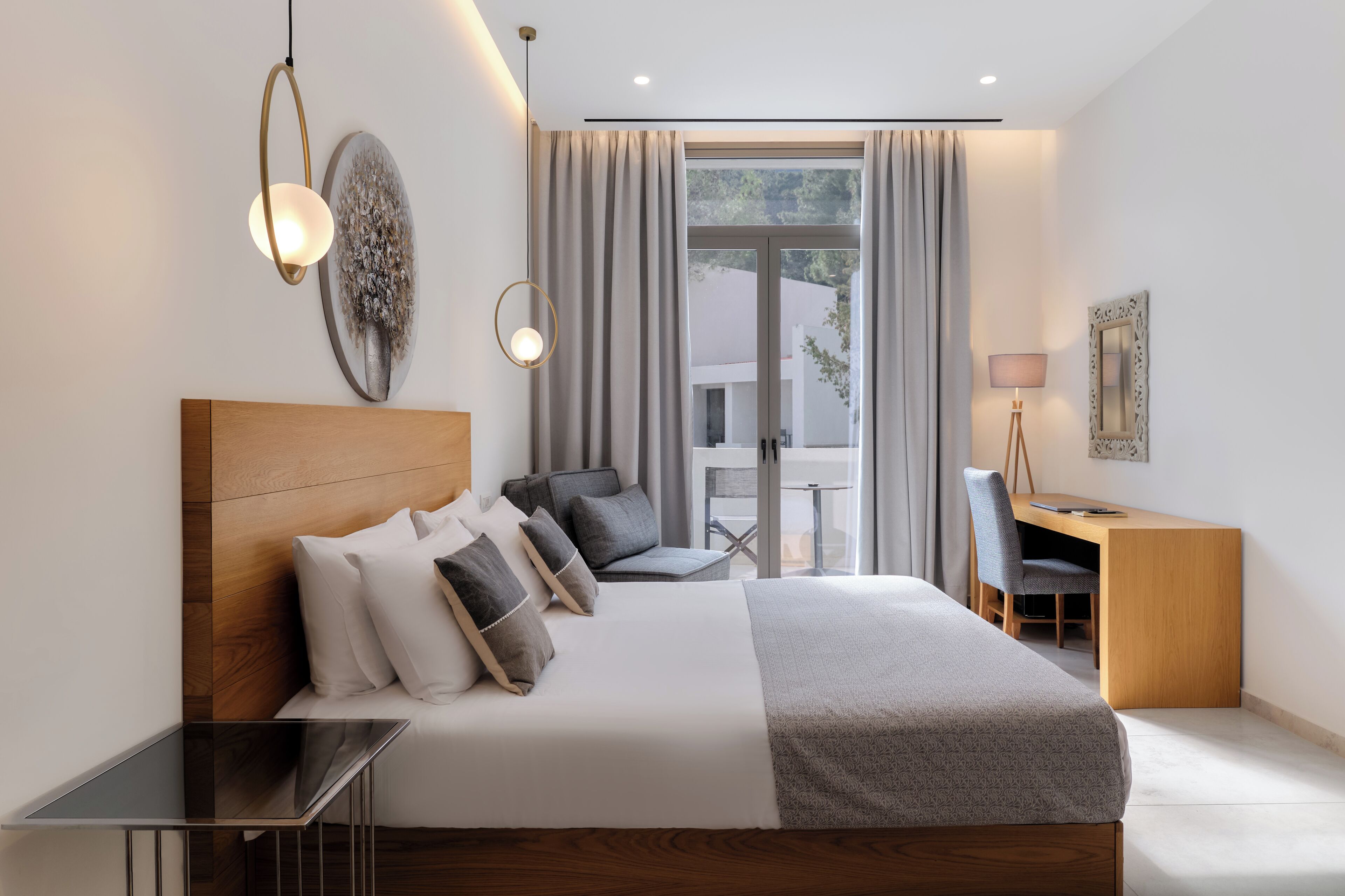 A modern bedroom with a large bed, a desk, and a chair, a small table, and a large window with curtains.