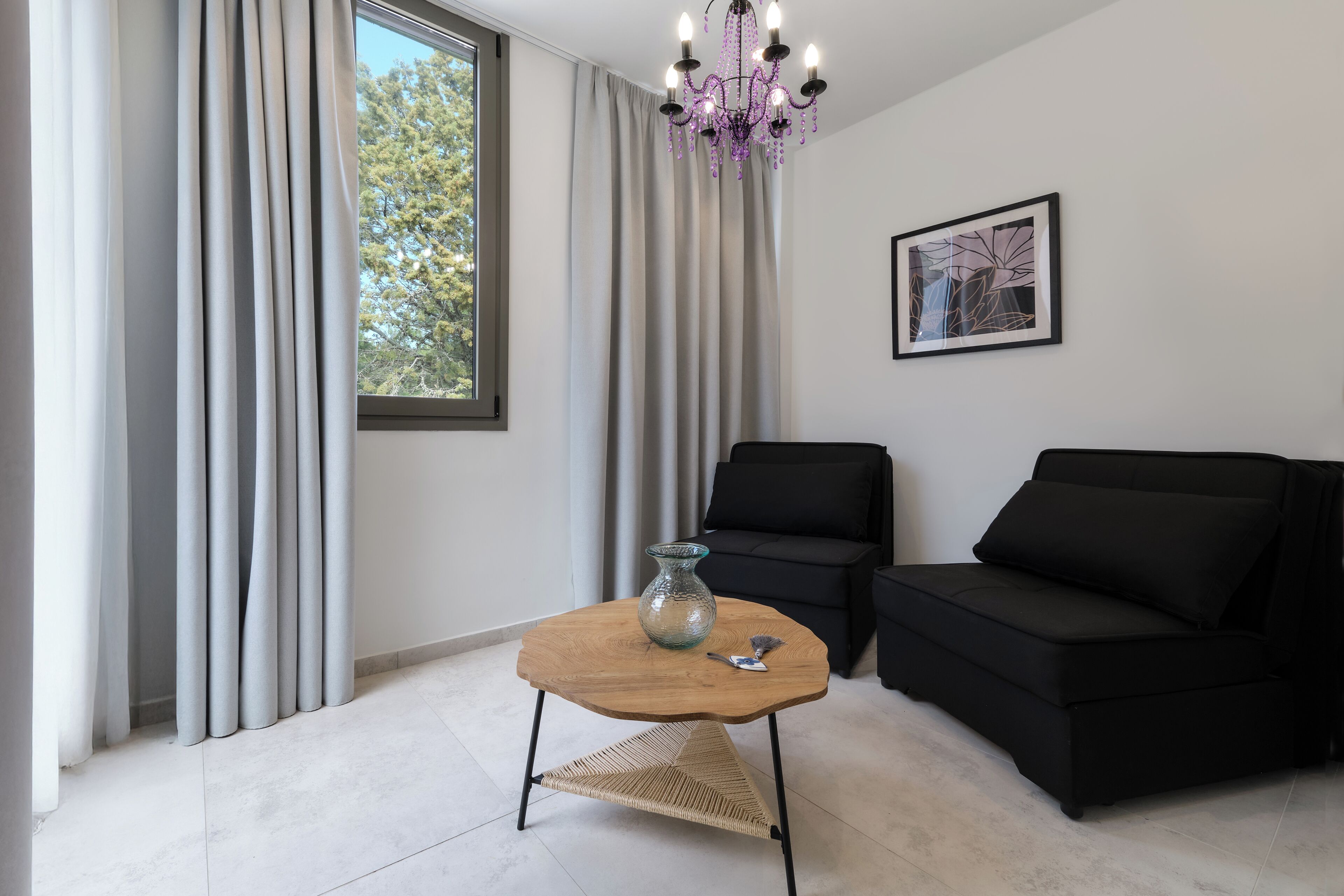 Uma sala de estar moderna com mesa de centro de madeira, sofá preto e um lustre.