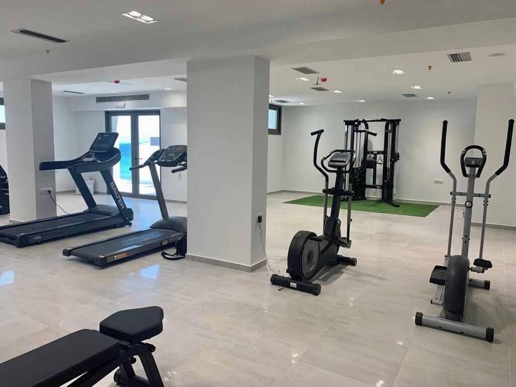 Ein Fitnessstudio mit Laufbändern, Crosstrainern und Kraftgeräten.