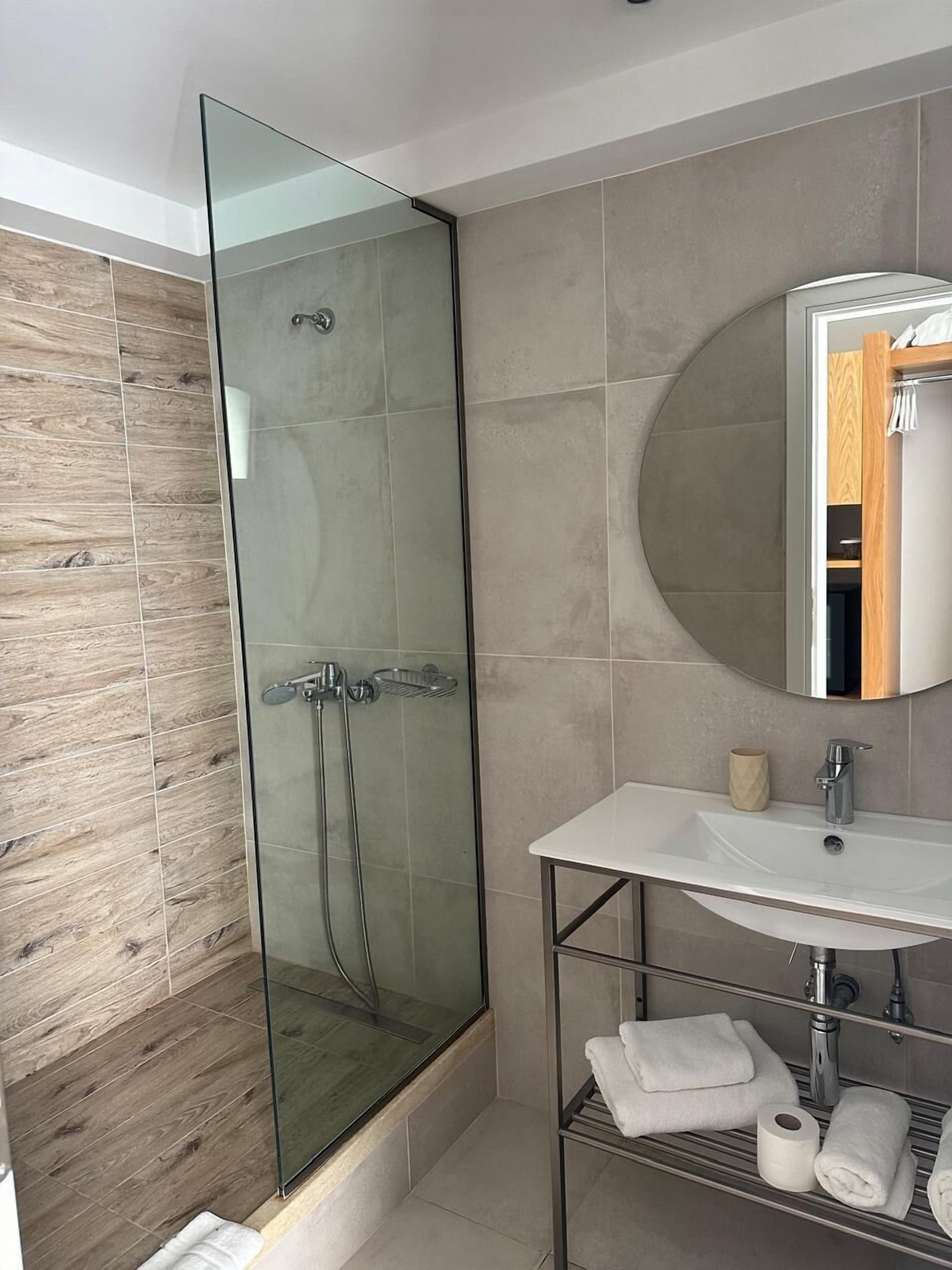 Une salle de bain moderne avec une douche à parois de verre, un lavabo blanc et un meuble-lavabo en bois.