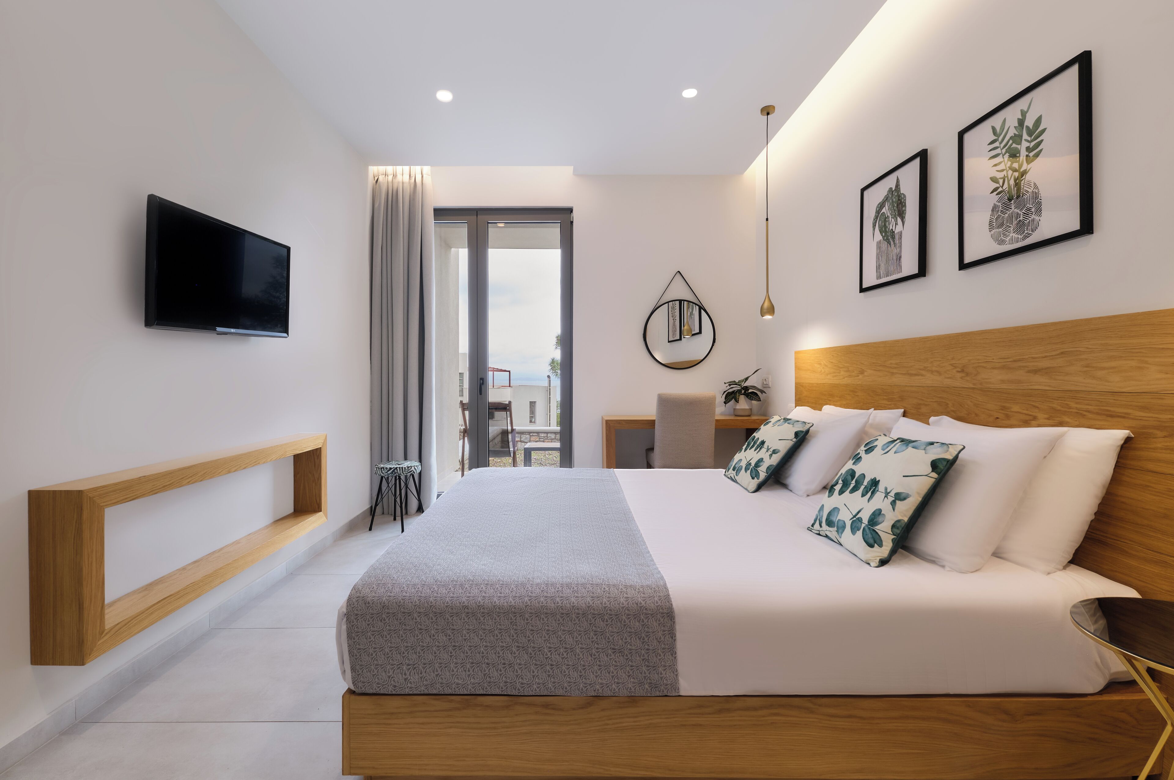 Habitación de hotel moderna con una cama grande, televisor montado en la pared y obras de arte en las paredes.