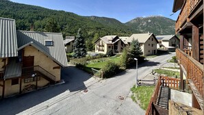Een rij chalets met schuine daken, een centrale weg en een bergachtige achtergrond.