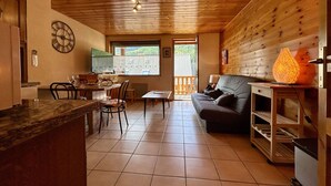 Een gezellig interieur van een chalet met een eethoek, keuken en een bank.
