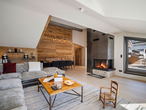Una sala de estar moderna con chimenea, un sofá, una mesa de centro y un comedor.