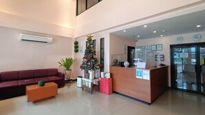 Zona de recepción con un sofá rojo, un árbol de Navidad y un mostrador de recepción.