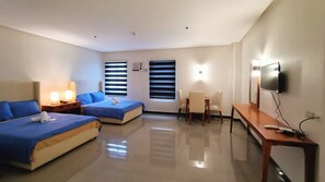 A hotel room with two beds, a desk, a chair, a TV, and a window with blinds. - Grand Emilia Hotel (Cebu City)