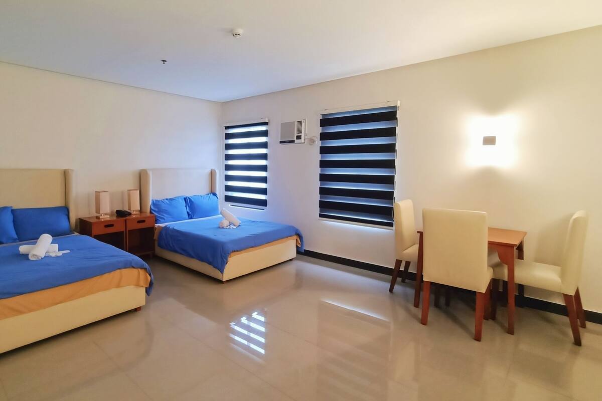 A hotel room with two beds, a desk, and a chair.