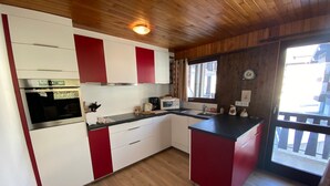 Une cuisine avec un plancher en bois, un four encastré, un four à micro-ondes et un évier.