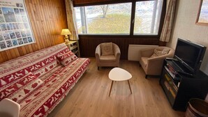Une pièce confortable avec un lit, deux canapés, une petite table, un téléviseur et une fenêtre donnant sur des arbres.