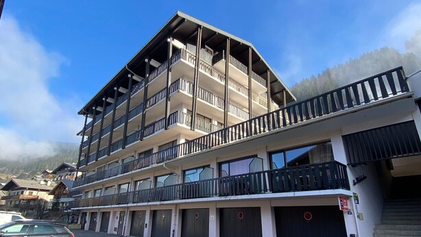 Un hôtel à plusieurs étages doté de balcons, d’un parking et offrant une vue sur les montagnes.