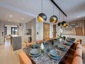 Uma sala de jantar moderna com uma mesa comprida posta para seis pessoas, com pratos, copos e talheres.