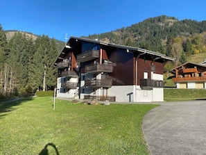 A multi-story building with balconies, set in a mountainous area with a clear sky.