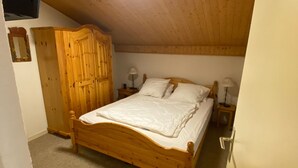 Una cama de madera en una habitación con techo inclinado y un armario de madera.