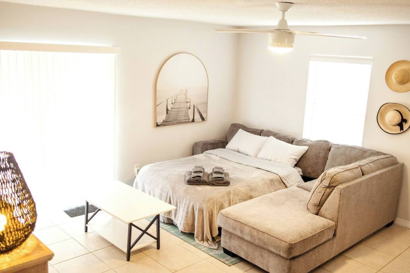 Un dormitorio acogedor con cama, sofá, mesa y ventilador de techo.