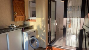 A compact laundry room with a washing machine, a drying rack, and a wooden cabinet. - Spacious Villa T2 + Mezzanine, AC, 6 Guests, Terrace, Parking, Close to Beach, Port Leucate (Port Leucate)