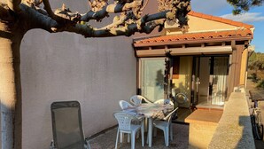 A patio with a table and chairs, a chair, a washing machine, and a bicycle. - Spacious Villa T2 + Mezzanine, AC, 6 Guests, Terrace, Parking, Close to Beach, Port Leucate (Port Leucate)
