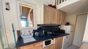 A compact kitchen with wooden cabinets, a microwave, a coffee maker, and a sink. - Spacious Villa T2 + Mezzanine, AC, 6 Guests, Terrace, Parking, Close to Beach, Port Leucate (Port Leucate)