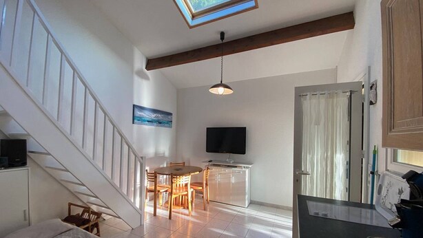 A spacious living area with a dining table, a sofa, a TV, and a staircase. - Spacious Villa T2 + Mezzanine, AC, 6 Guests, Terrace, Parking, Close to Beach, Port Leucate (Port Leucate)