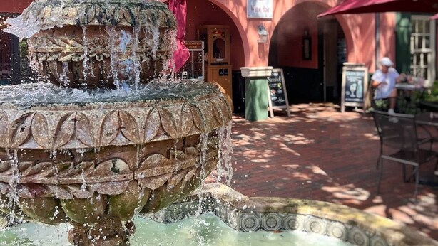 A courtyard with a fountain, a wine bar, and a restaurant named St. Augustine Candle. - Historic St. Augustine Balcony Suite with Parking (Saint Augustine)