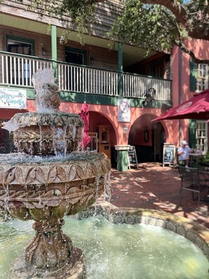 A courtyard with a fountain, a wine bar, and a restaurant named St. Augustine Candle. - Historic St. Augustine Balcony Suite with Parking (Saint Augustine)
