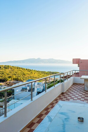 A rooftop terrace with a view of the sea and mountains, a checkered floor, and a metal railing. - Sunny Holiday (Sarandë)