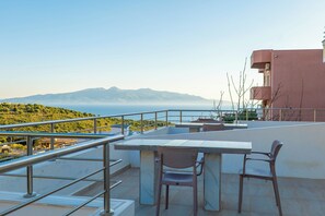 A terrace with a table and chairs, overlooking a body of water and distant mountains. - Sunny Holiday (Sarandë)