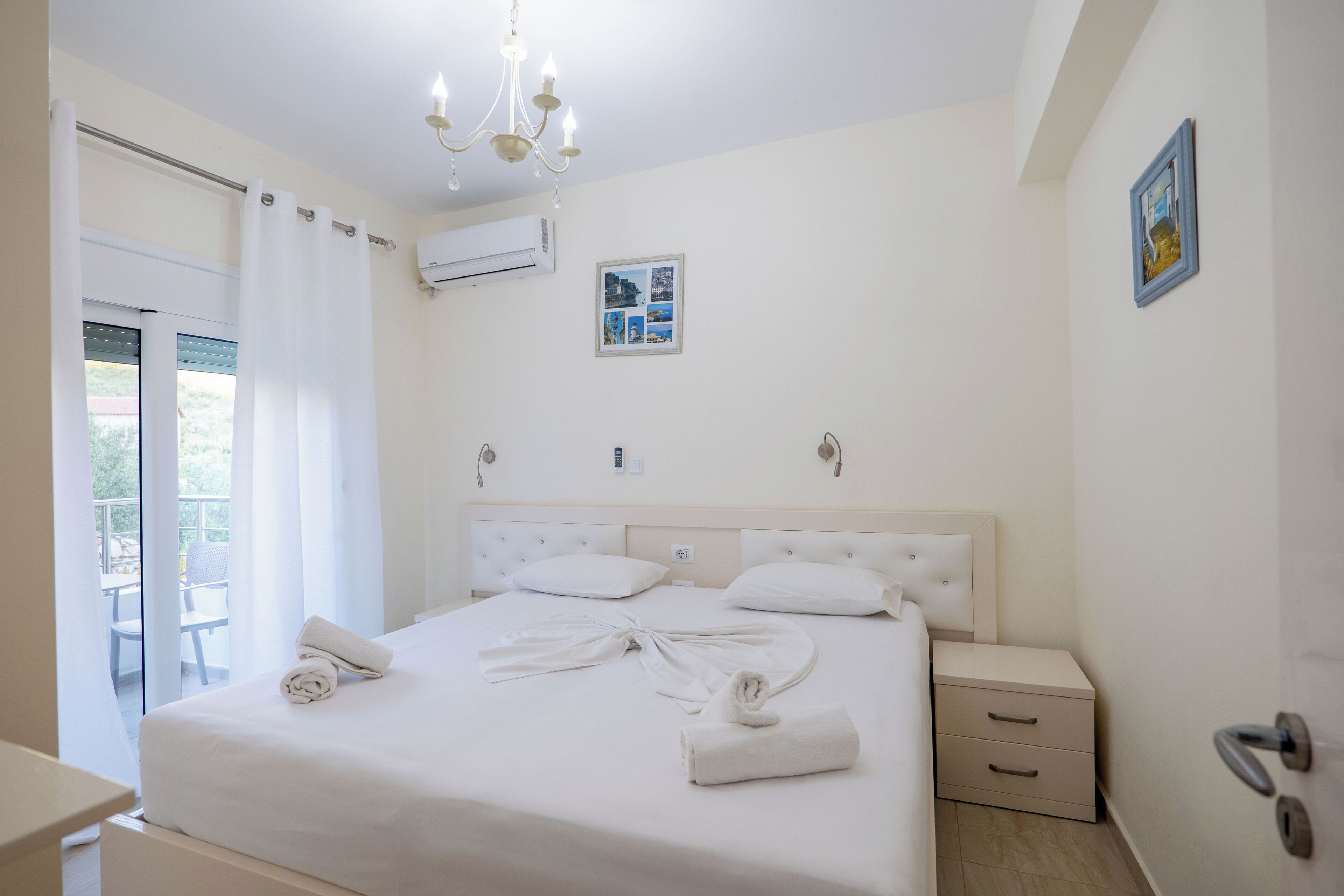 Camera d'albergo con un letto, un comodino, un lampadario, un quadro appeso e vista all'esterno.
