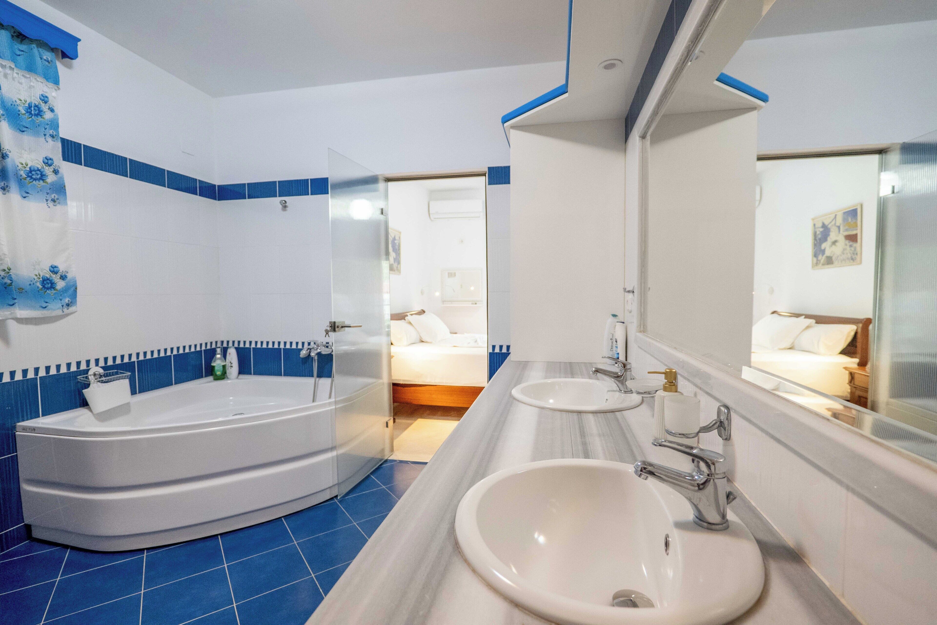 Un baño con bañera, dos lavamanos y un espejo grande.