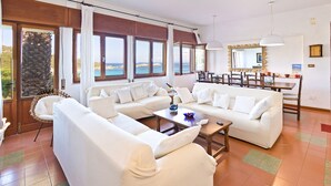 Ein großzügiges Wohnzimmer mit einer gemütlichen Sofaecke, einem Couchtisch und einem Essbereich mit Stühlen und Tisch.