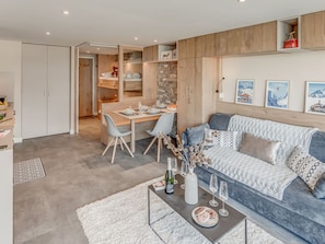 A modern living room with a sofa, coffee table, and a dining area with a table set for two.