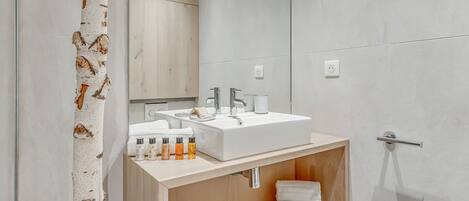 A modern bathroom with a wooden vanity, a large mirror, and a white sink.