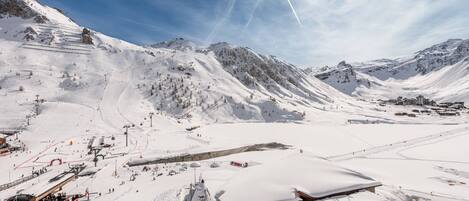 A snow-covered mountain landscape with ski slopes, a ski lift, and a small lodge.