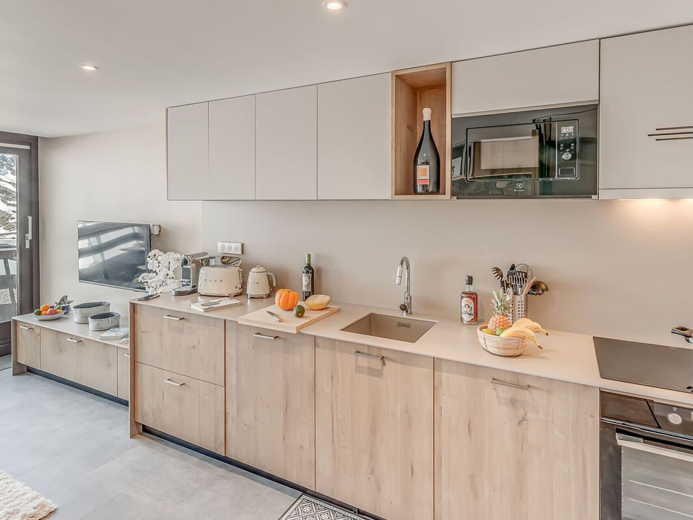 A modern kitchen with a large island, built-in microwave, and a wine bottle on the countertop.