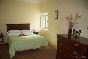 Un dormitorio con cama, cómoda, mesita de noche y ventana.