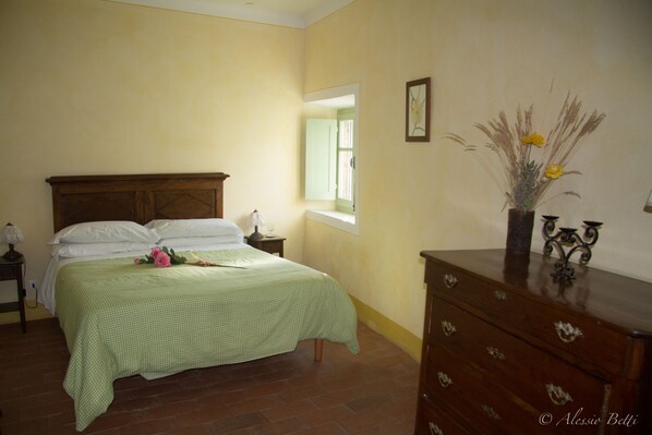 Une chambre à coucher avec un lit, une commode, une table de chevet et une fenêtre.