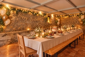 Une longue table à manger, dressée pour une fête d’anniversaire, avec des bougies, des fleurs et un gâteau.