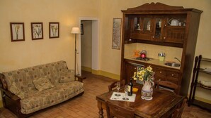 A living room with a sofa, wooden dining table, chairs, a cabinet, and a vase with flowers. - La Casatorre di Ponticello. Casale di campagna con ampio giardino e piscina (Cantiere-ponticello)