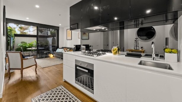 A modern kitchen with white cabinetry, a black countertop, and stainless steel appliances. - StayCentral - Hawthorn East Elegance with Study (Hawthorn East)