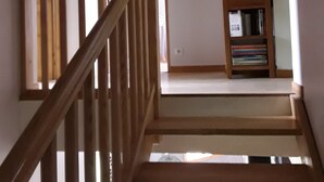 Una escalera de madera que lleva a un rellano con una estantería.