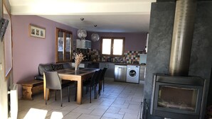 Una cocina moderna con comedor, lavadora y estufa de leña.