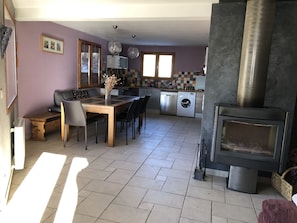 A modern kitchen with a dining area, a washing machine, and a wood-burning stove.