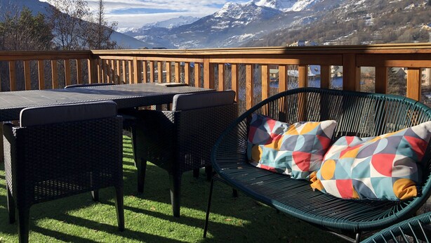 Una terraza con mesa y sillas, con vistas a un paisaje montañoso.
