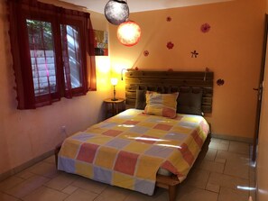 A bedroom with a bed, a nightstand, a lamp, and a window with curtains.
