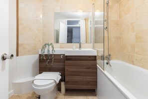 A modern bathroom with a toilet, sink, and bathtub. - Amazing Flat in Battersea (London)