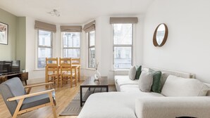 A modern living room with a sofa, chairs, a coffee table, and a television. - Amazing Flat in Battersea (London)