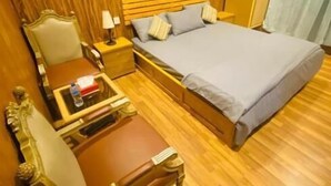 Una habitación con paneles de madera, una cama, una mesita de noche, una silla y una pequeña mesa.